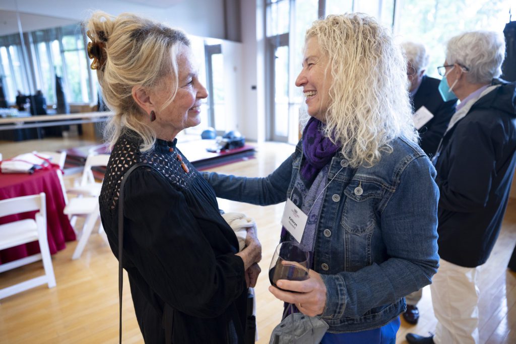 Two blond friends embrace and smile at each other.