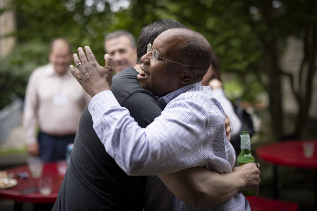 Garry Jenkins hugs a friend who is holding a beer bottle.