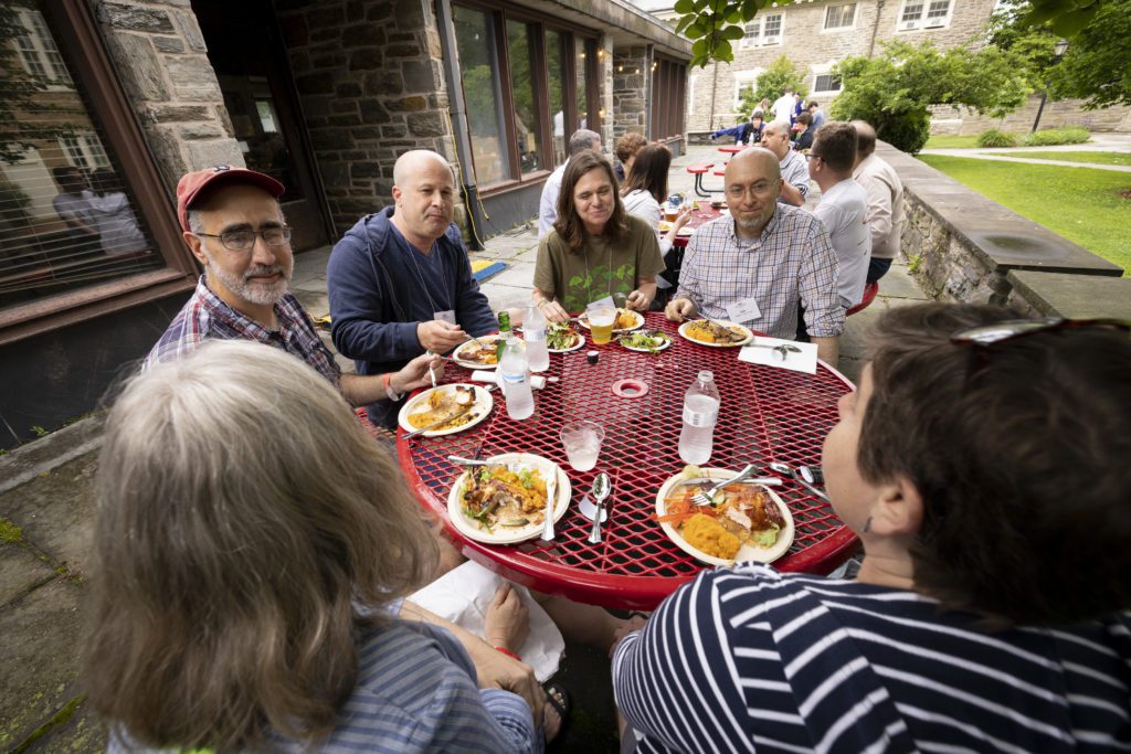 Six alumni sit around a table outside the DC for dinner.