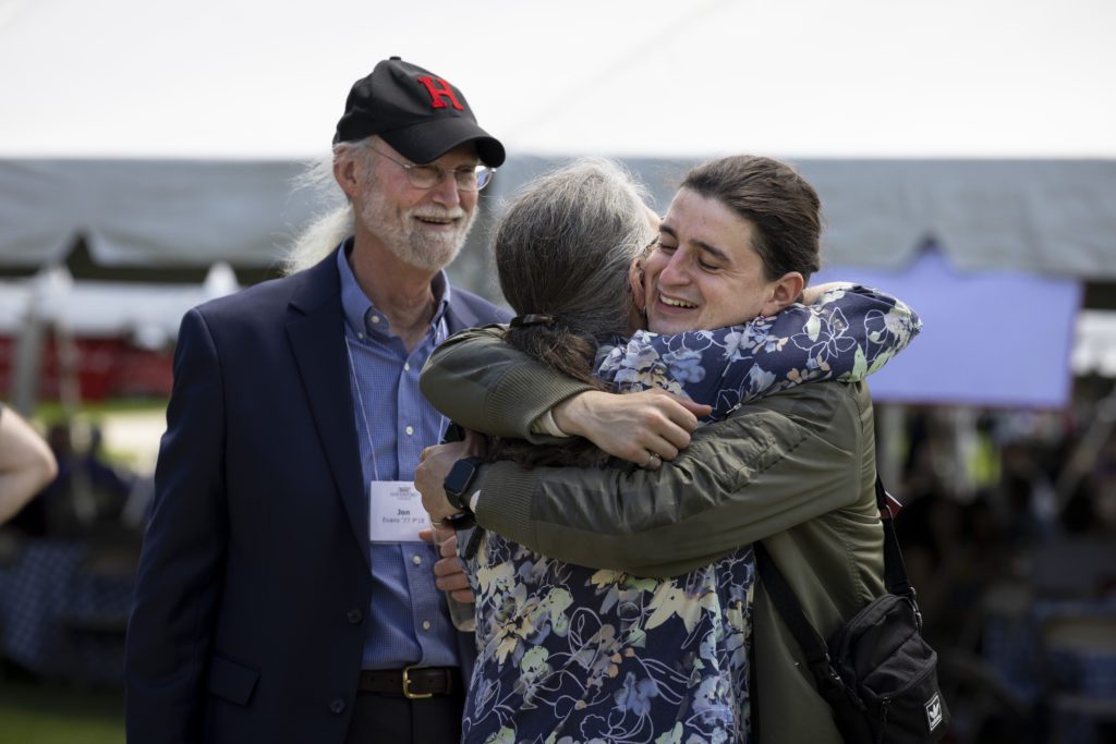 Holden and Melissa embrace while John, wearing a Haverford cap, looks on smiling.