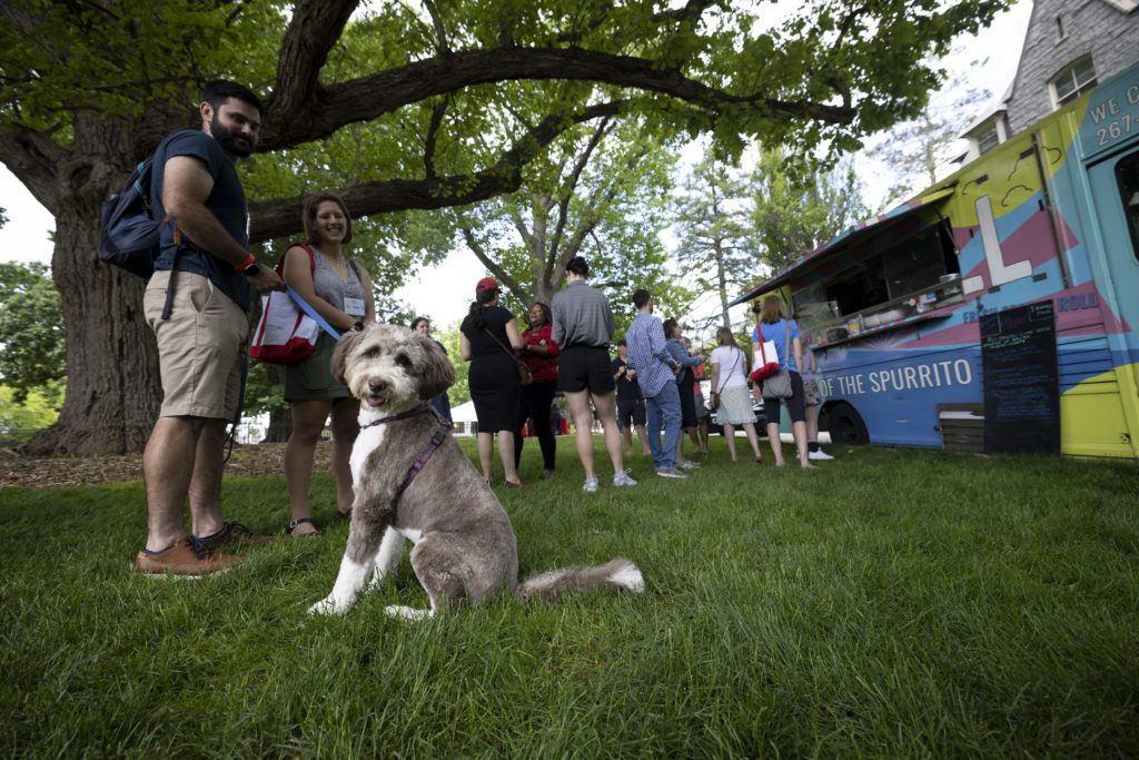 A cute dog and his owners wait in line for one of the food trucks at lunch on Saturday.