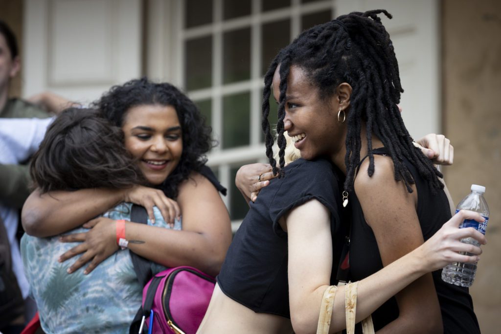 Two alumni hug two of their friends in front of Founders.