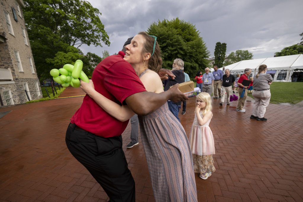 An alum hugs a member of Dining Services staff as the gray clouds behind them threaten rain.