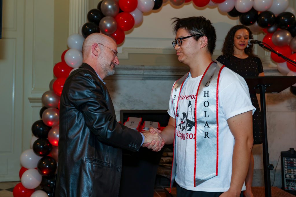Junior Nguyen shakes Jeff Tecosky-Feldman's hand after receiving his Chesick Scholar sash