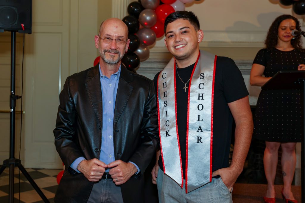 Brandon poses in his Chesick Scholar sash with Jeff and a balloon arch in the background.