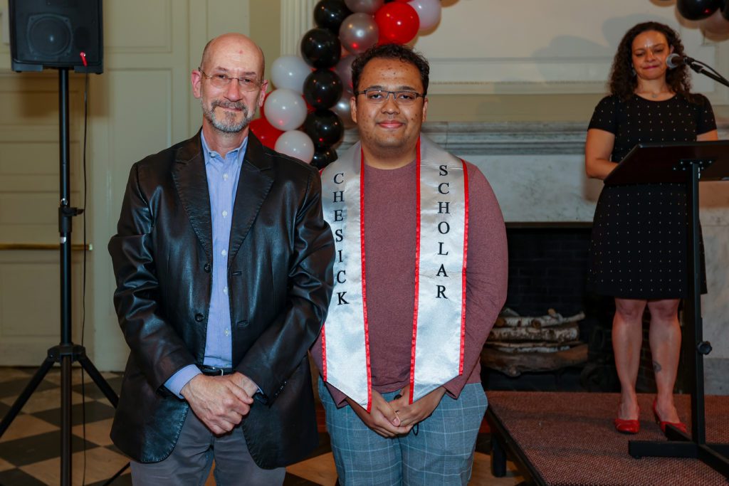 Roy Simamora and Jeff Tecosky-Feldman with Christina Rose and an arch of black, gray, white, and red balloons in the background.