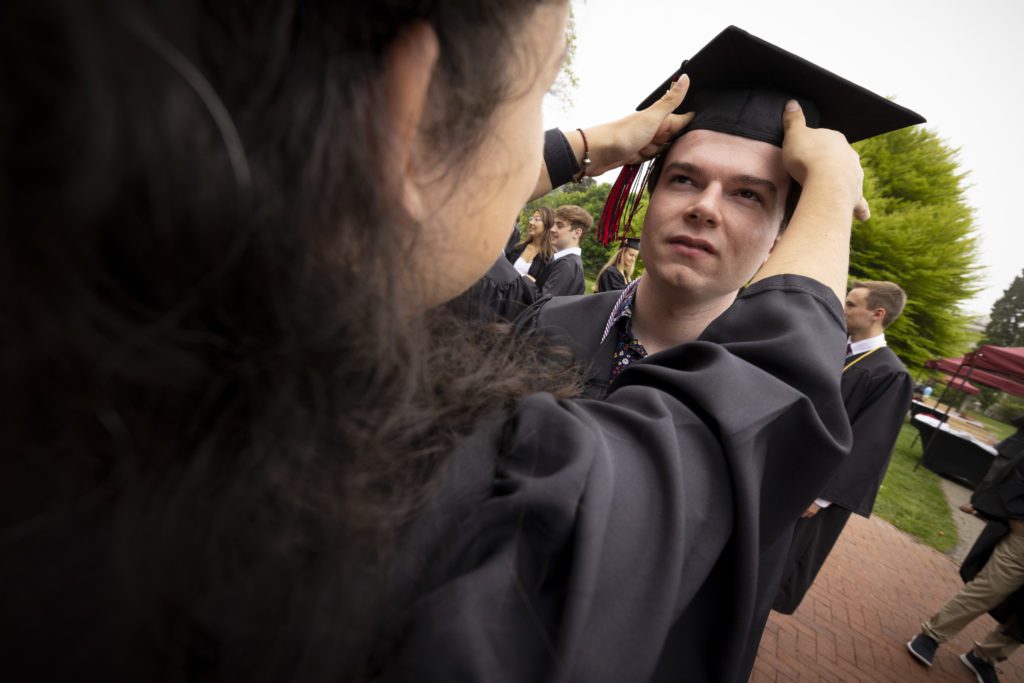 A student adjusts a cap on her friends head.
