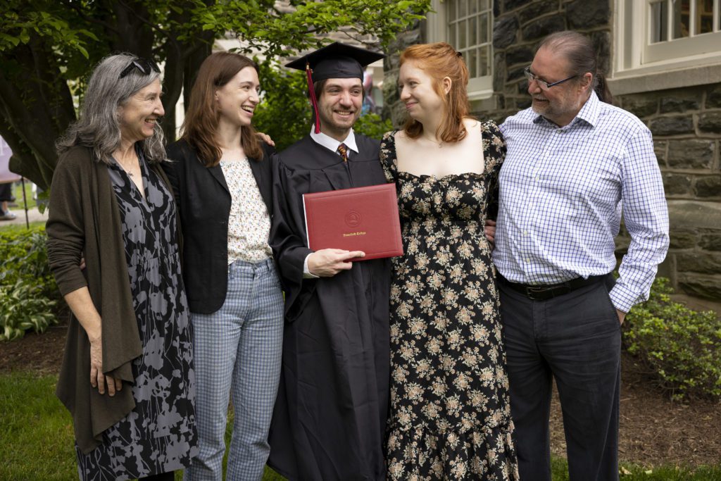 A student poses with his family and his diploma.