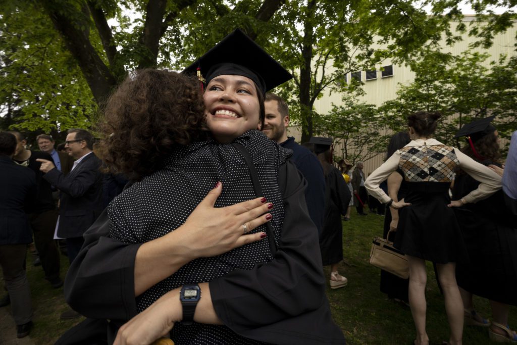 A student hugs a family member on Founders Green