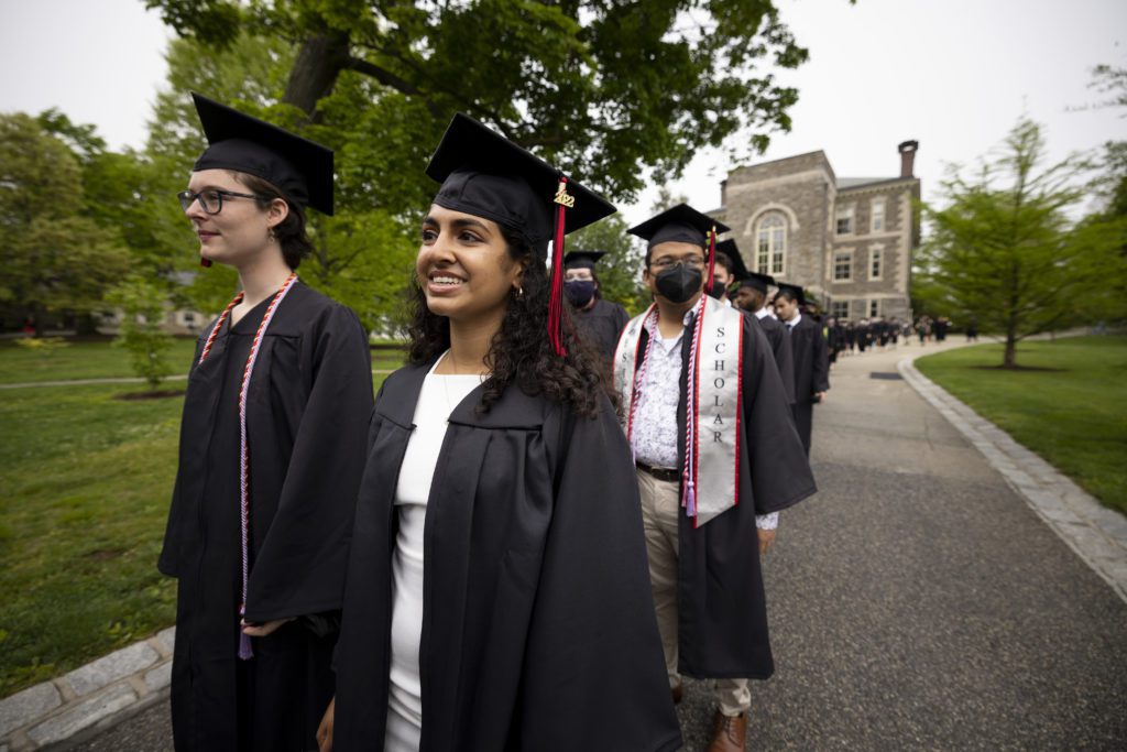 Students walk two-by-two in their caps and gowns from Founders to the Field House