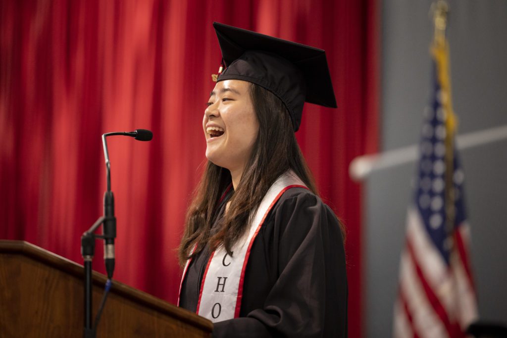 Che Young Annette Lee smiles at the podium, the American flag visible in the background