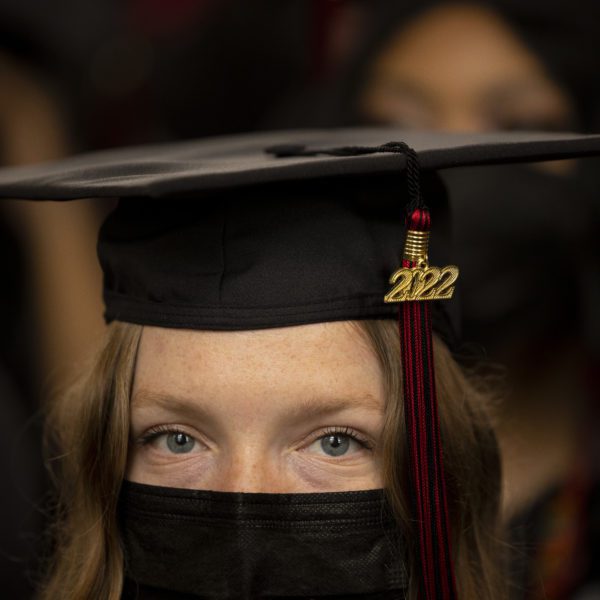 A close-up of a student's masked face and the 2022 dangling from their graduation cap