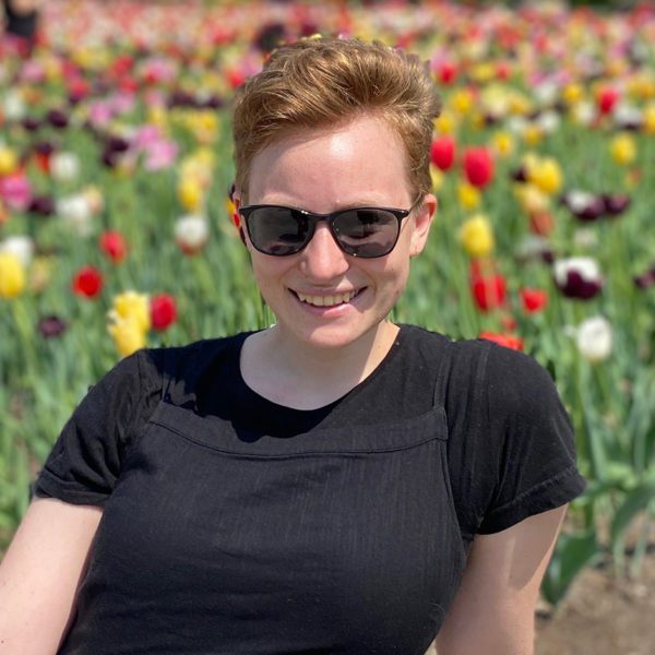 Alissa Vandenbark '22 sits in front of a field of flowers.