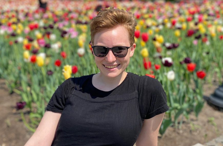 Alissa Vandenbark '22 sits in front of a field of flowers.