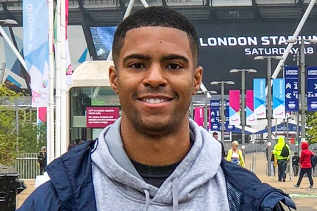 Anthony Walker smiles while standing on a street outside.
