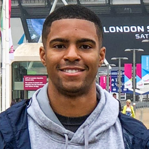 Anthony Walker smiles while standing on a street outside.