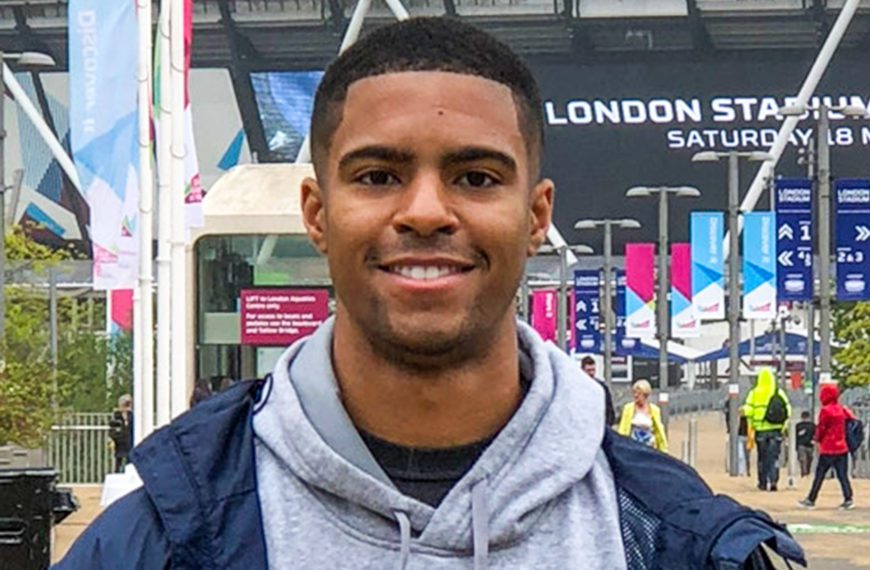 Anthony Walker smiles while standing on a street outside.
