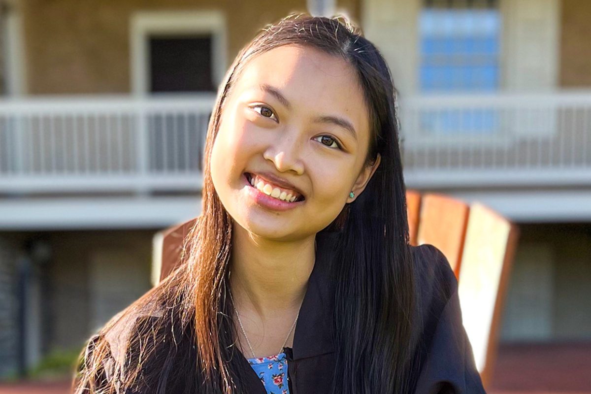 Nuria Inez Benitez '22 sits in a chair on Founder's Green, smiling.