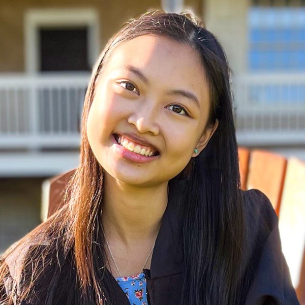 Nuria Inez Benitez '22 sits in a chair on Founder's Green, smiling.
