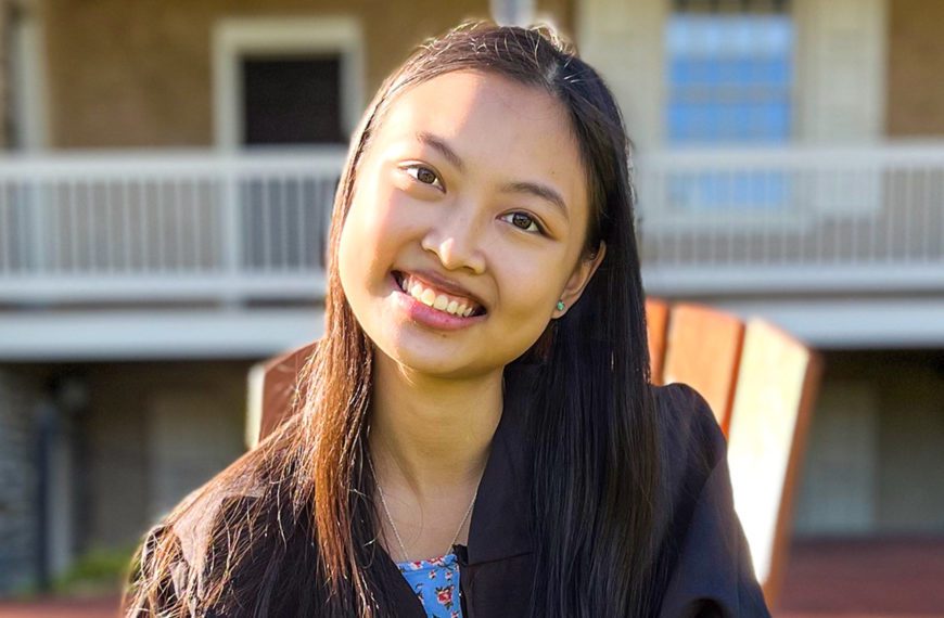 Nuria Inez Benitez '22 sits in a chair on Founder's Green, smiling.
