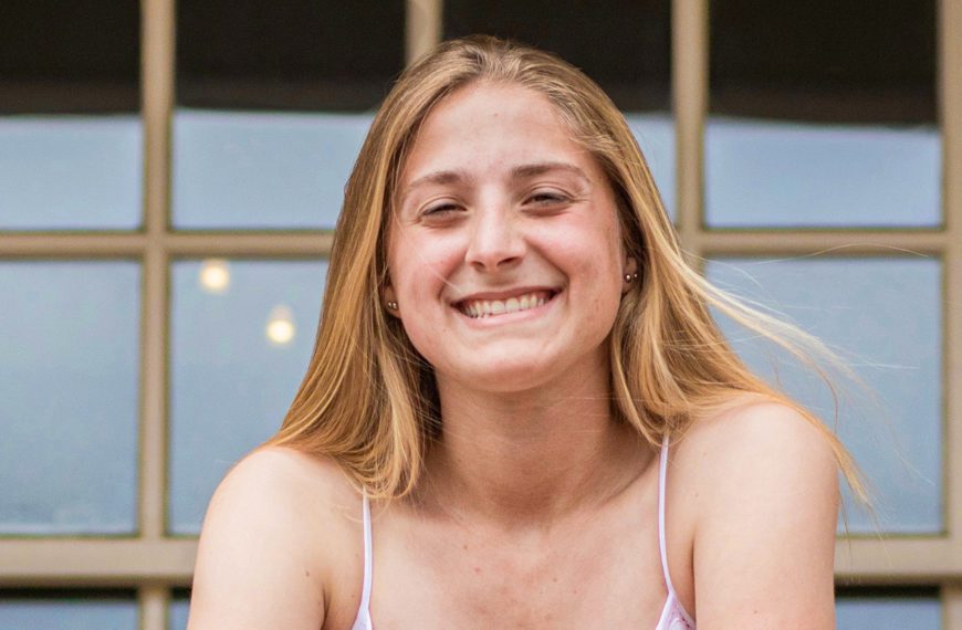 Julie Rebh '22 stands on Founder's Porch, leaning on the railing.