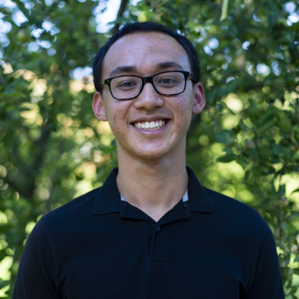 Theo smiles to the camera with trees in the background