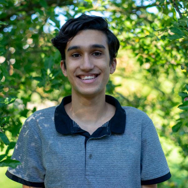 João smiles for the camera with trees in the background