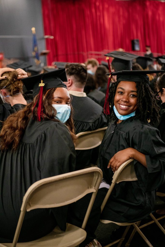 Two women turn around in their seats to smile at the camera.