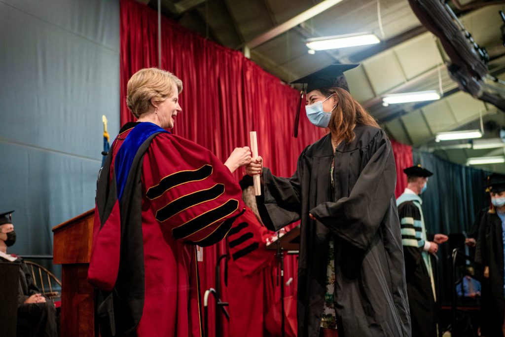 Wendy Raymond hands one member of the Class of 2020 her diploma as she walks across the stage.