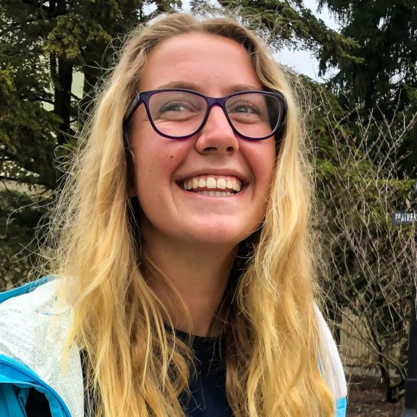 Riah Newfont '22 smiles in front of a tree.