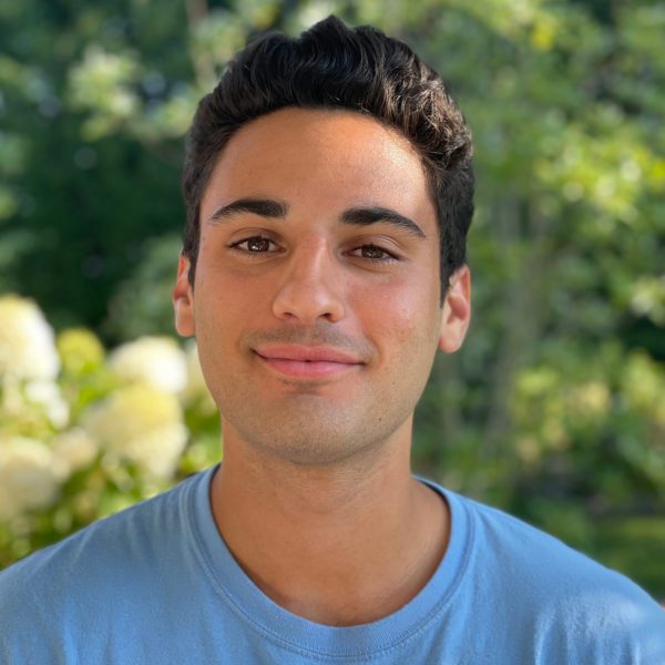 Jackson Trevor '22 stands in front of a background of foliage.