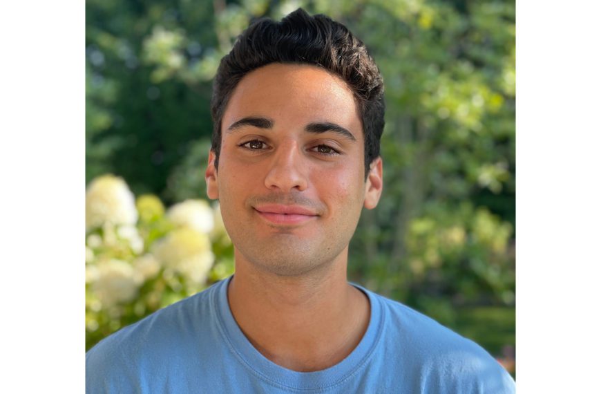 Jackson Trevor '22 stands in front of a background of foliage.