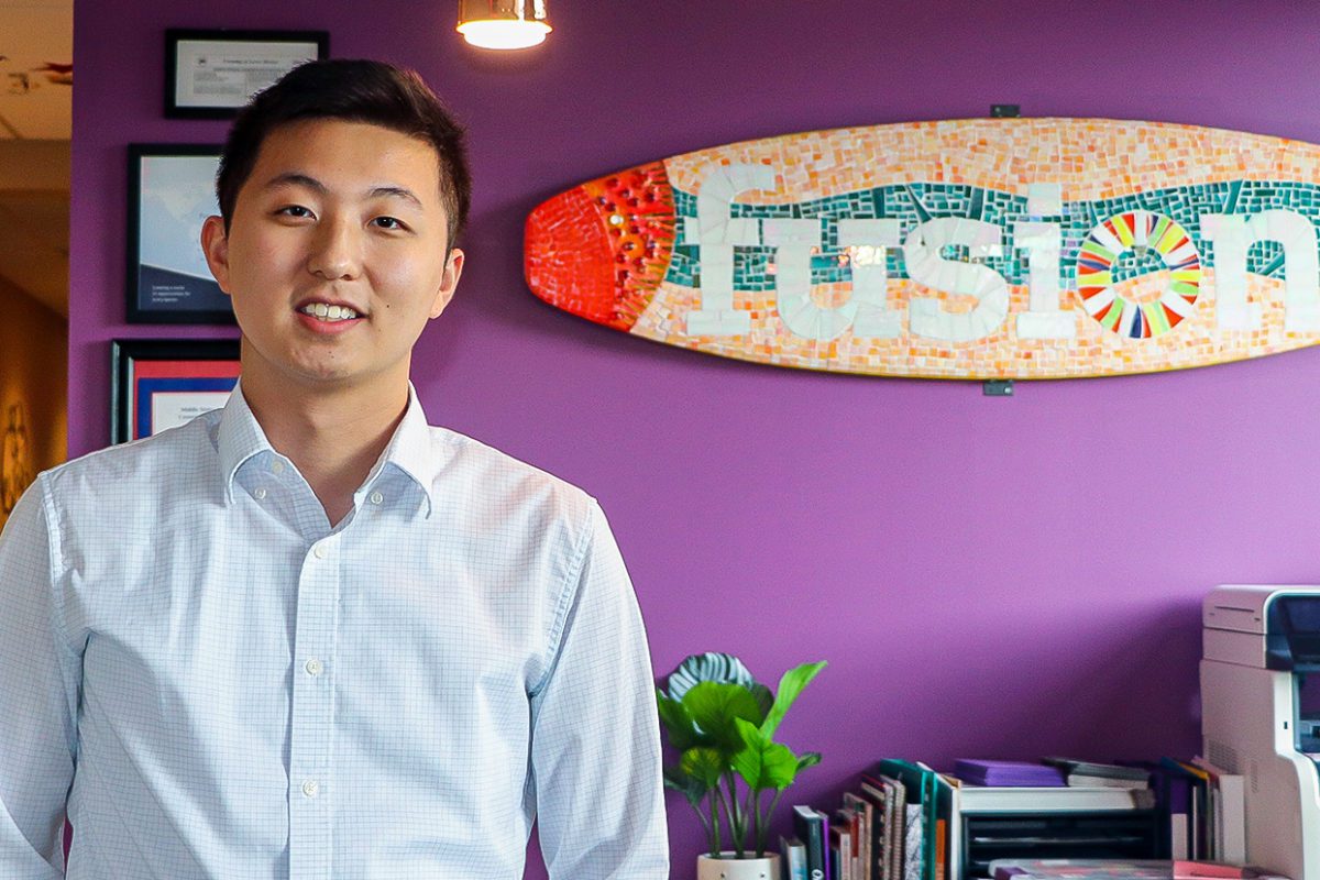 Felix Qin '22 stands in front of a sign for Fusion Academy, where he works. Photo by Aby Isakov '24.