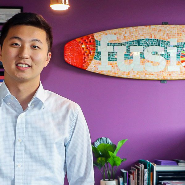 Felix Qin '22 stands in front of a sign for Fusion Academy, where he works. Photo by Aby Isakov '24.