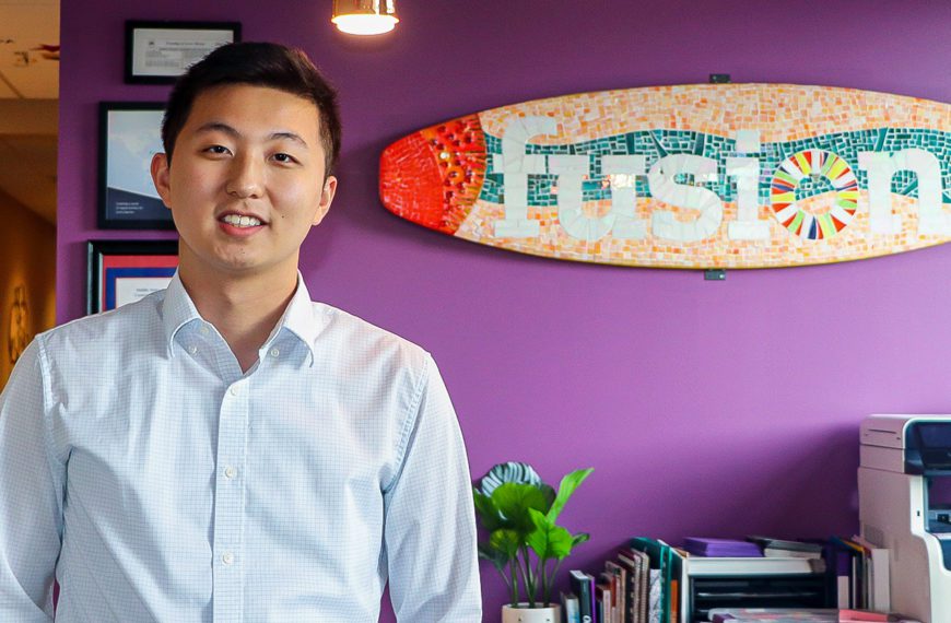 Felix Qin '22 stands in front of a sign for Fusion Academy, where he works. Photo by Aby Isakov '24.