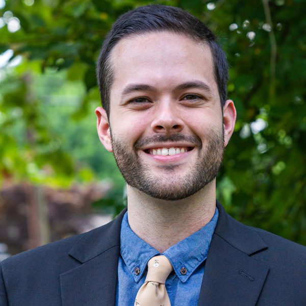 Ryan Totaro '22 stands in front of a background of trees. Photo by Patrick Montero.