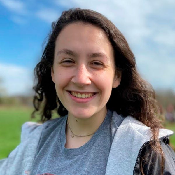 Rebecca smiles for the camera, green field in the background