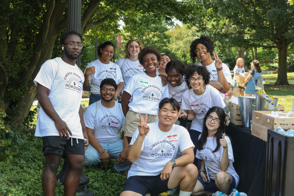 11 Students in Chesick Scholar Horizons t-shirts pose, giving thumbs ups and peace signs to the camera.