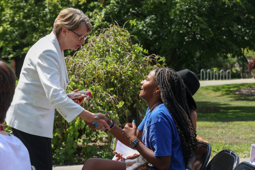 A student shakes the hand of President Wendy Raymond.