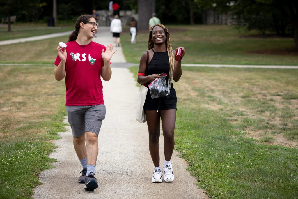 Two students, one wearing a red RSL shirt, laugh walking on Founders Green.