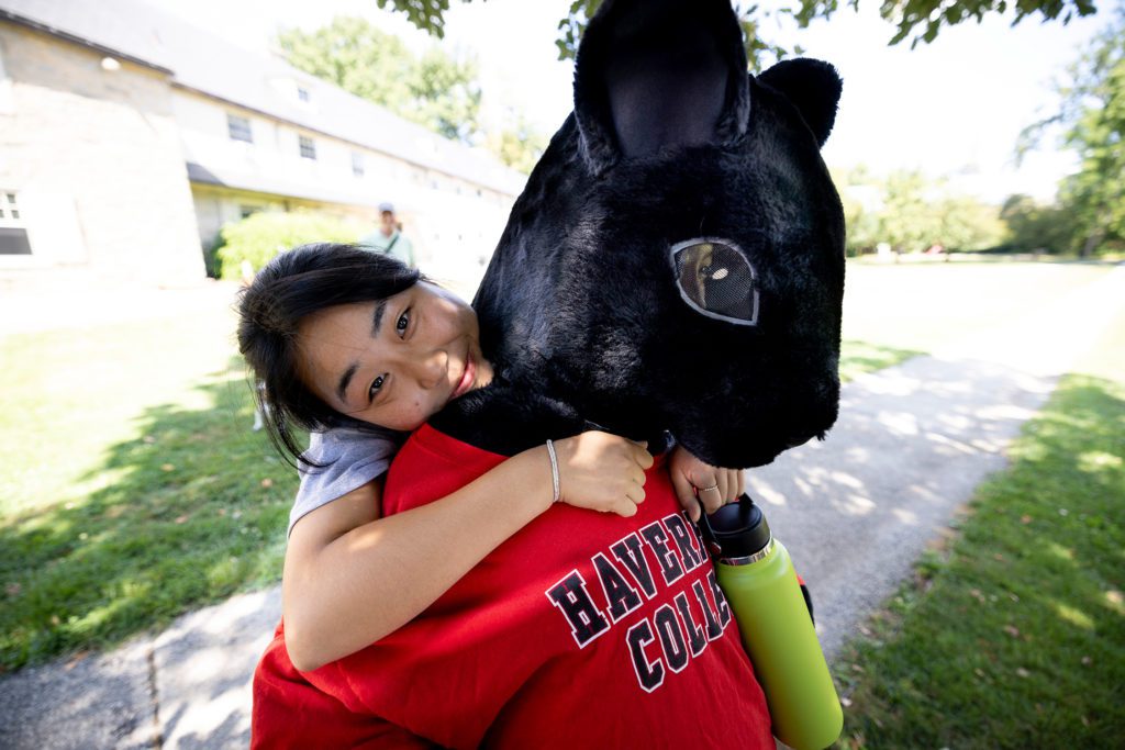A student embraces the Black Squirrel mascot from behind.