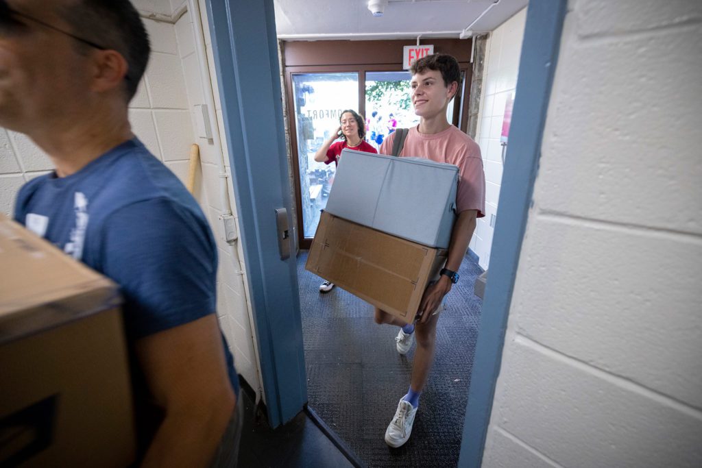 A student carries two boxes into Comfort Hall