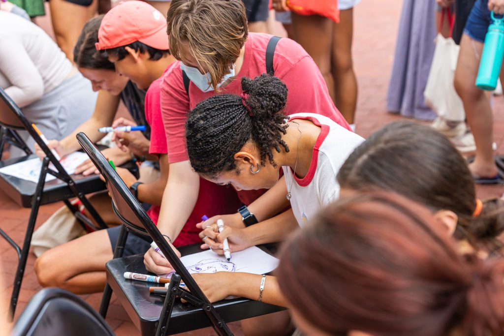 Students lean on chairs to speed draw Wendy Raymond.
