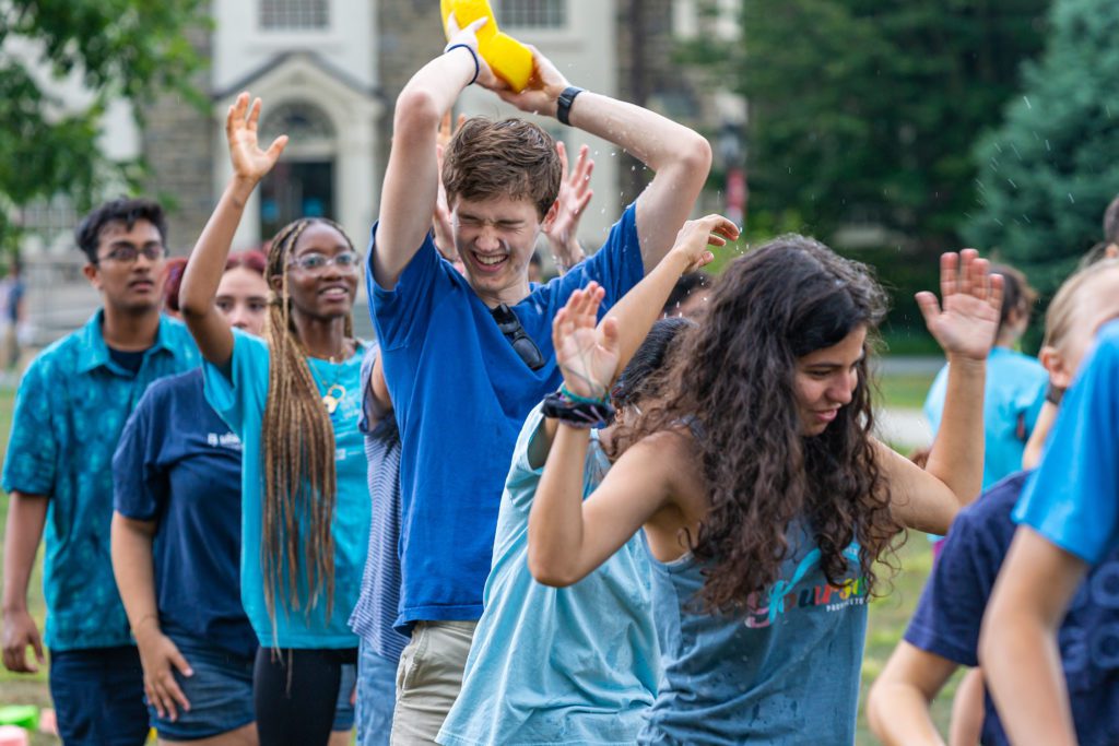 The blue team pass a wet sponge in a race.