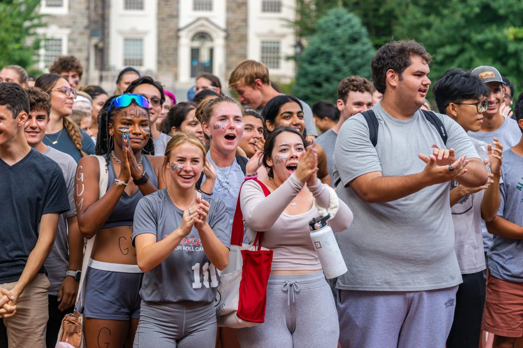 Members of the gray team, many wearing face paint, cheer.