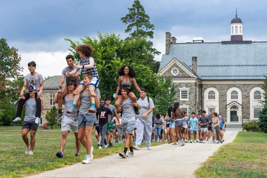 The Gray Gummere team enters Dorm Olympics with several team members on others' shoulders.
