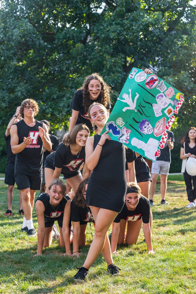 Six Jones team members make a human pyramid while another holds a handmade Jones sign.