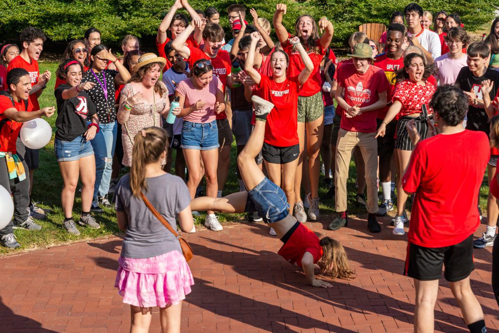 A student on the red team break dances as their team cheers behind them.