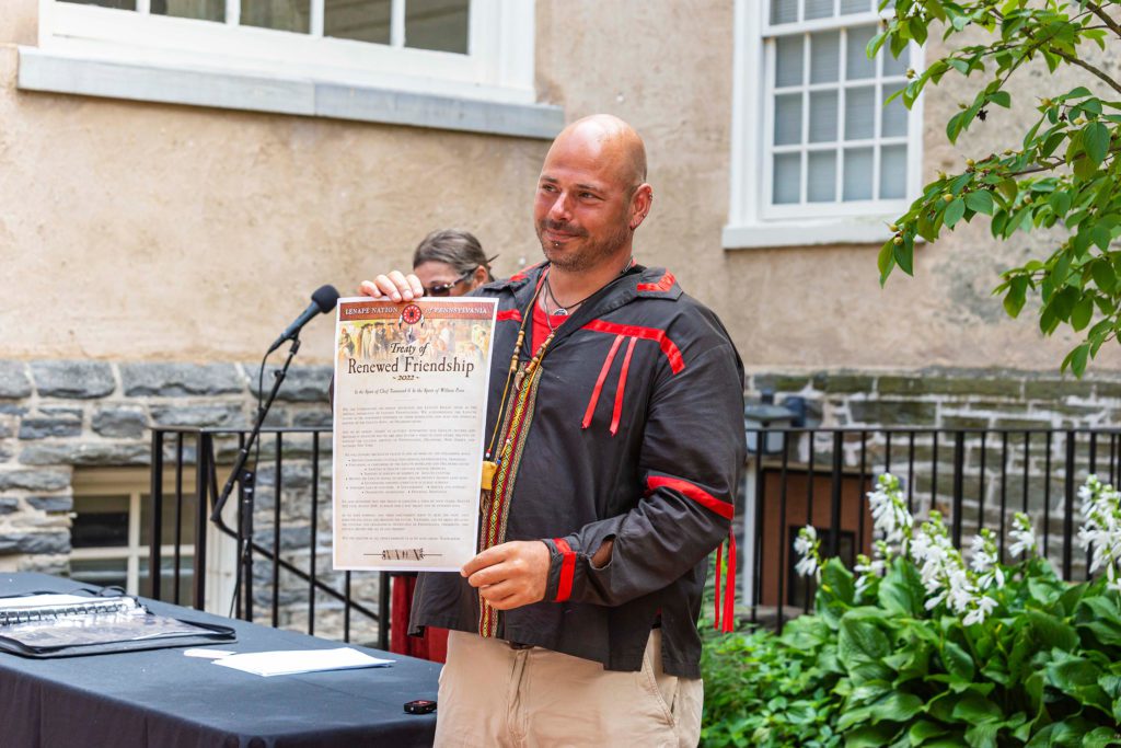 Adam holds up the treaty for the audience to read it.