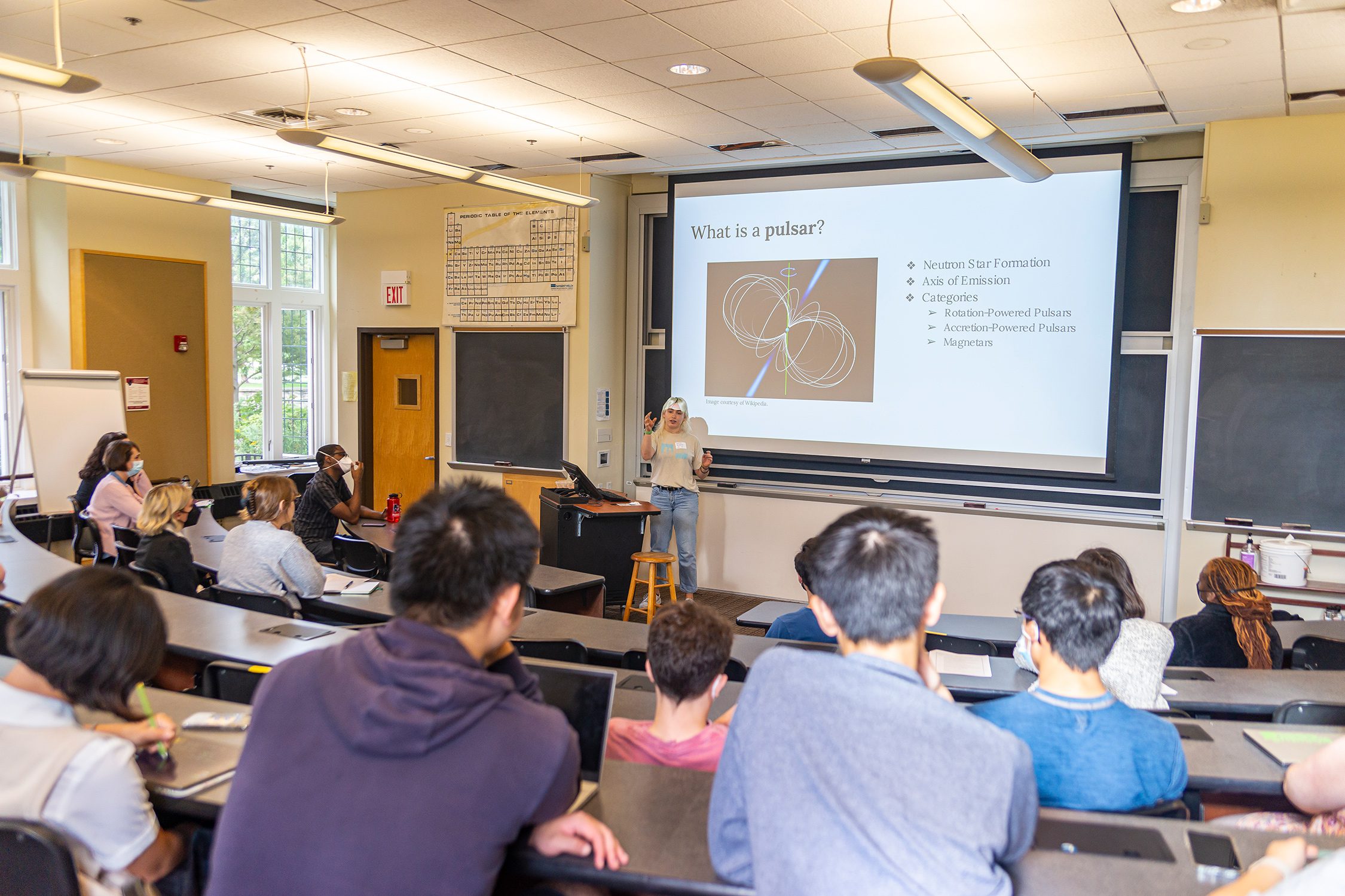Danika Rasmussen '23 stands in front of an audience, discussing their research. Danika Rasmussen '23 presents their research about pulsars. Photo by Patrick Montero.